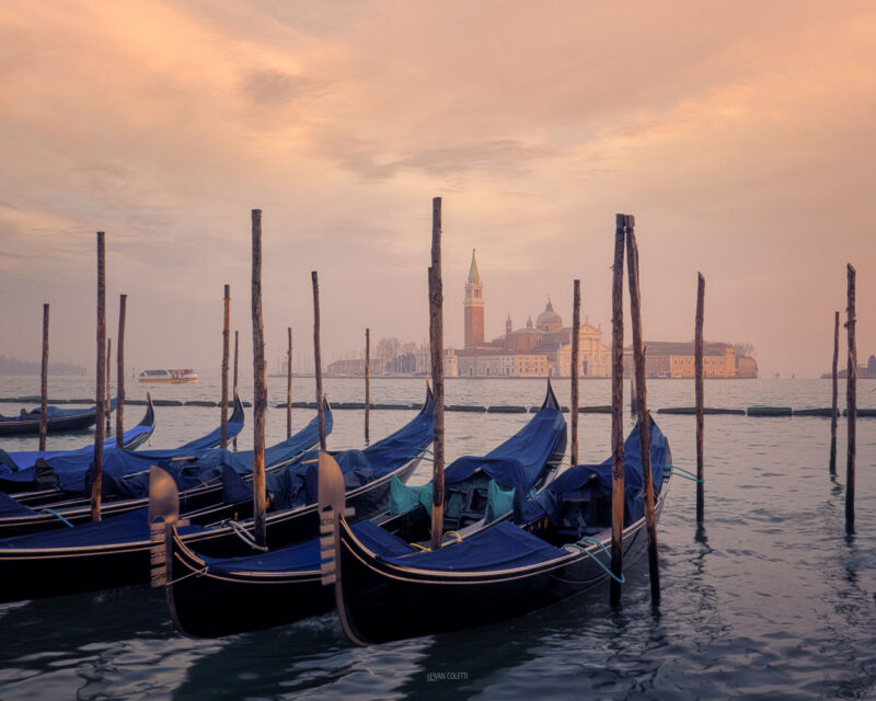 Traditional gondolas floating on the Venetian Lagoon at sunrise with the island of San Giorgio Maggiore in the background, Venice, Italy.