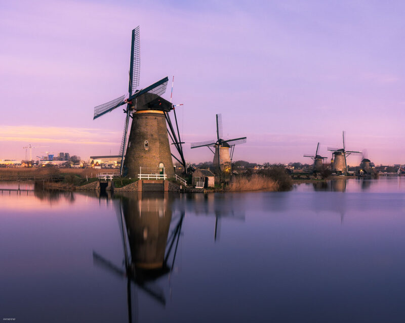 Historic windmills reflected in the calm canals during Kinderdijk Illumination Week in the Netherlands.