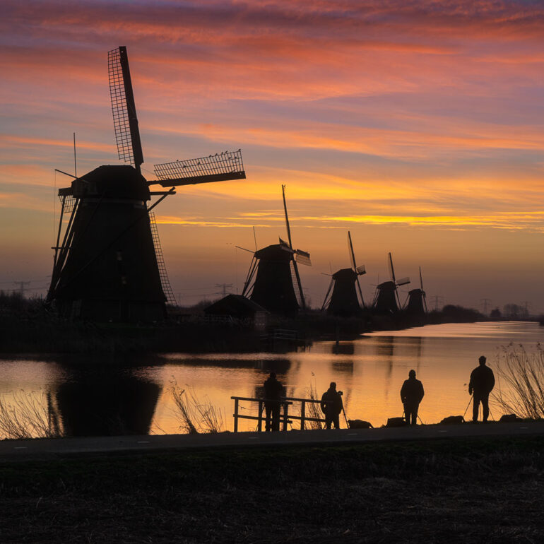 Home Historic windmills of Kinderdijk reflected in calm water during a golden sunrise in the Netherlands, a UNESCO World Heritage Site.