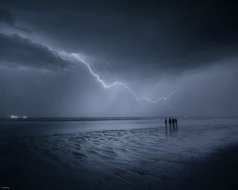 People watching a dramatic lightning storm over the North Sea from the beach at Noordwijk, the Netherlands.