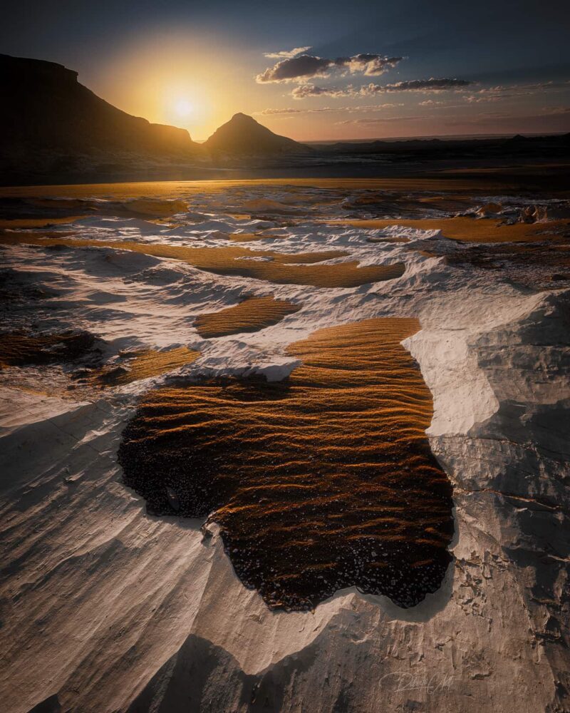 Golden sand dunes and white chalk formations illuminated by sunrise in Agabat Valley, part of Egypt