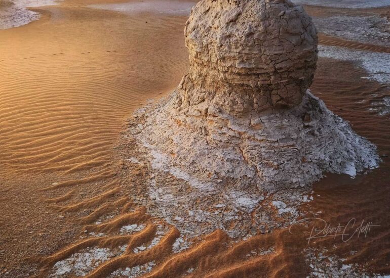 White chalk rock formation illuminated by the golden light of sunrise in White Desert National Park, Egypt.