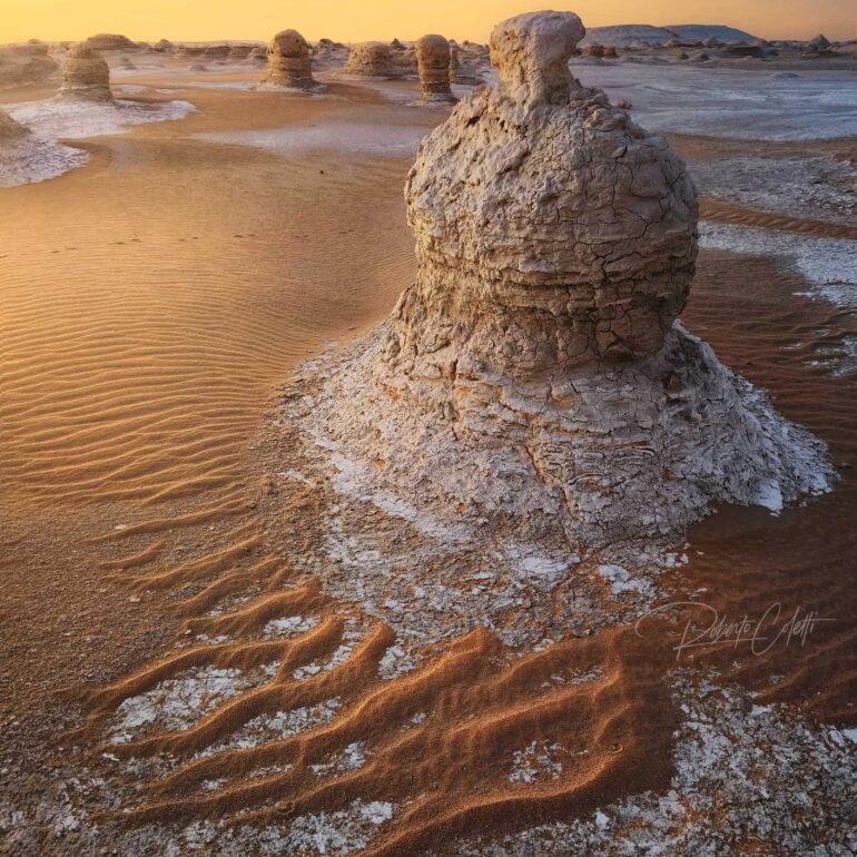White chalk rock formation illuminated by the golden light of sunrise in White Desert National Park, Egypt.