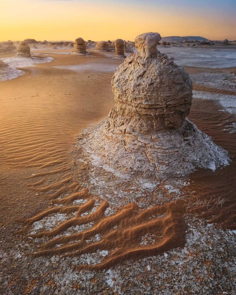 White chalk rock formation illuminated by the golden light of sunrise in White Desert National Park, Egypt.