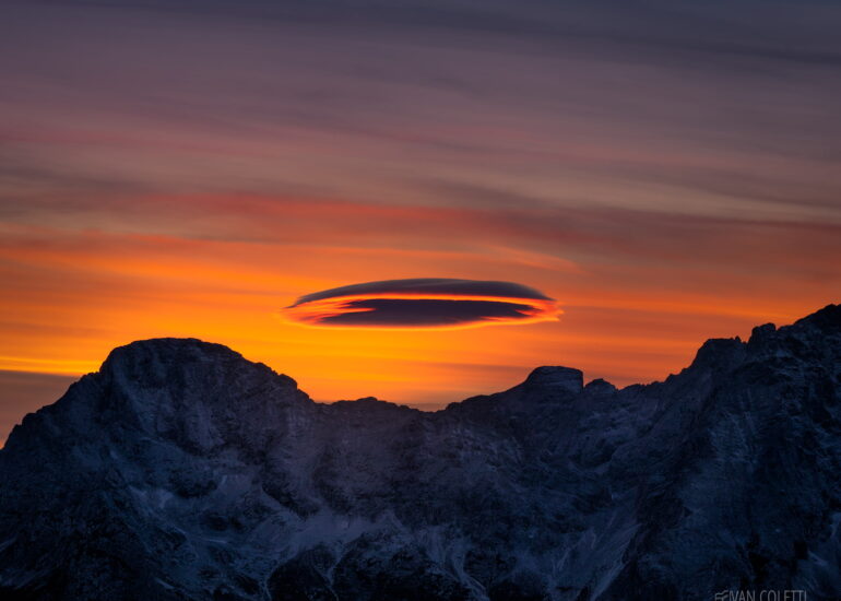 A rare lenticular cloud forming above Monte Rite in the UNESCO-listed Dolomites, Italy, creating a spectacular mountain weather phenomenon.