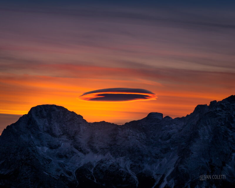 A rare lenticular cloud forming above Monte Rite in the UNESCO-listed Dolomites, Italy, creating a spectacular mountain weather phenomenon.