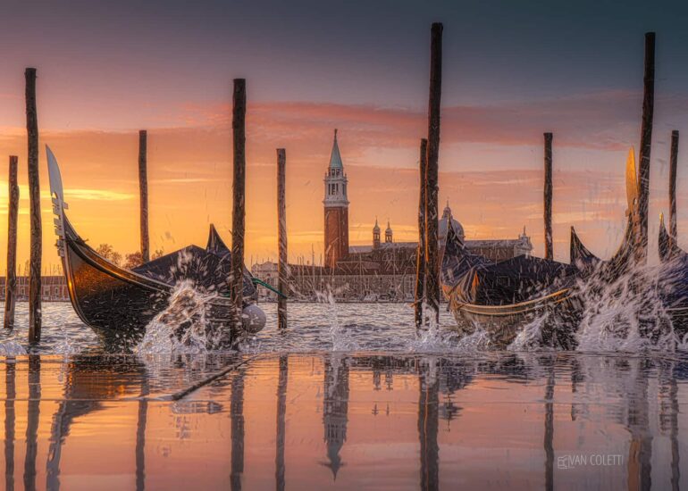 Gondolas floating on the high tide beneath a spectacular colourful sunrise, with San Giorgio Maggiore Island in the background, Venice, Italy.