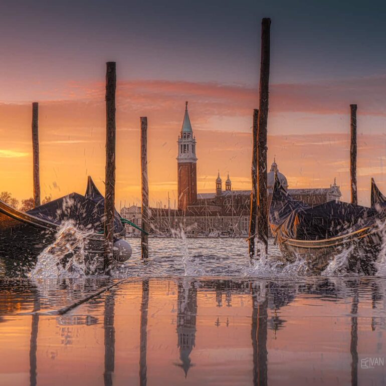 Gondolas floating on the high tide beneath a spectacular colourful sunrise, with San Giorgio Maggiore Island in the background, Venice, Italy.