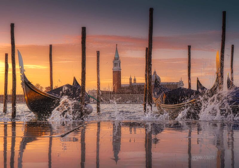 Gondolas floating on the high tide beneath a spectacular colourful sunrise, with San Giorgio Maggiore Island in the background, Venice, Italy.