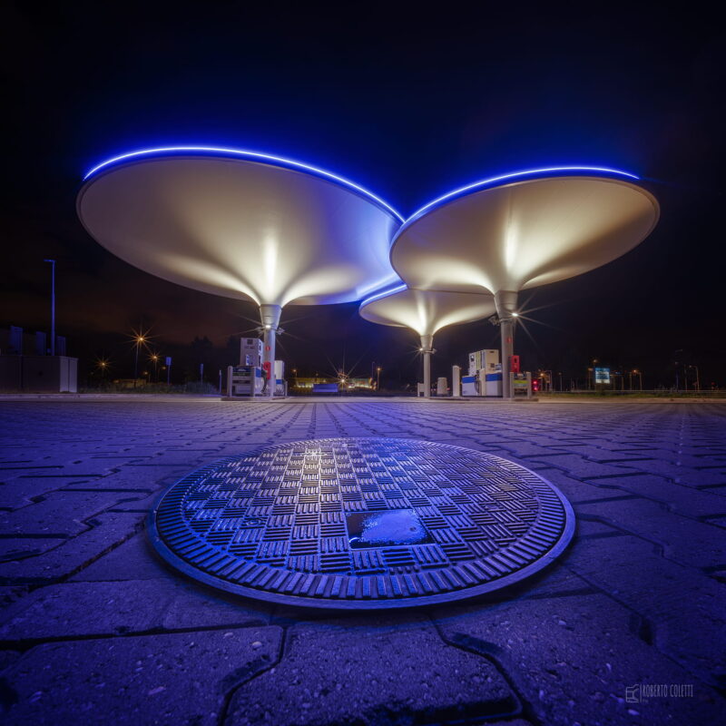 Illuminated gas station at night in the Netherlands, standing alone beneath the dark sky in a minimalist landscape.