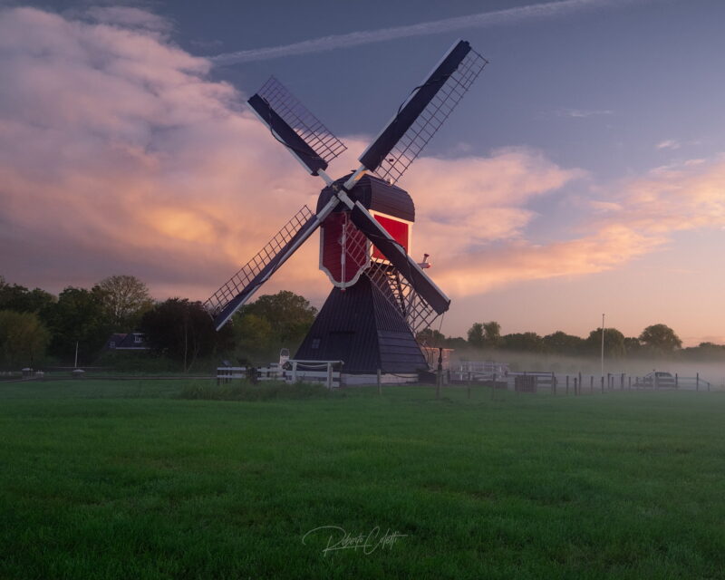 Historic red Dutch windmill surrounded by morning fog in Zuilen, Utrecht, the Netherlands.