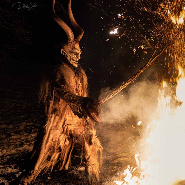 Traditional Krampus costume with carved wooden mask, fur and horns during a December celebration in Italy.