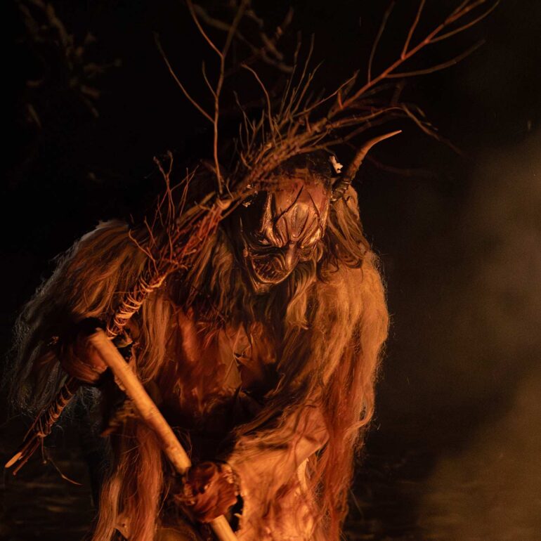 Krampus performer carrying a burning torch during the traditional winter celebration in the Italian Alps.