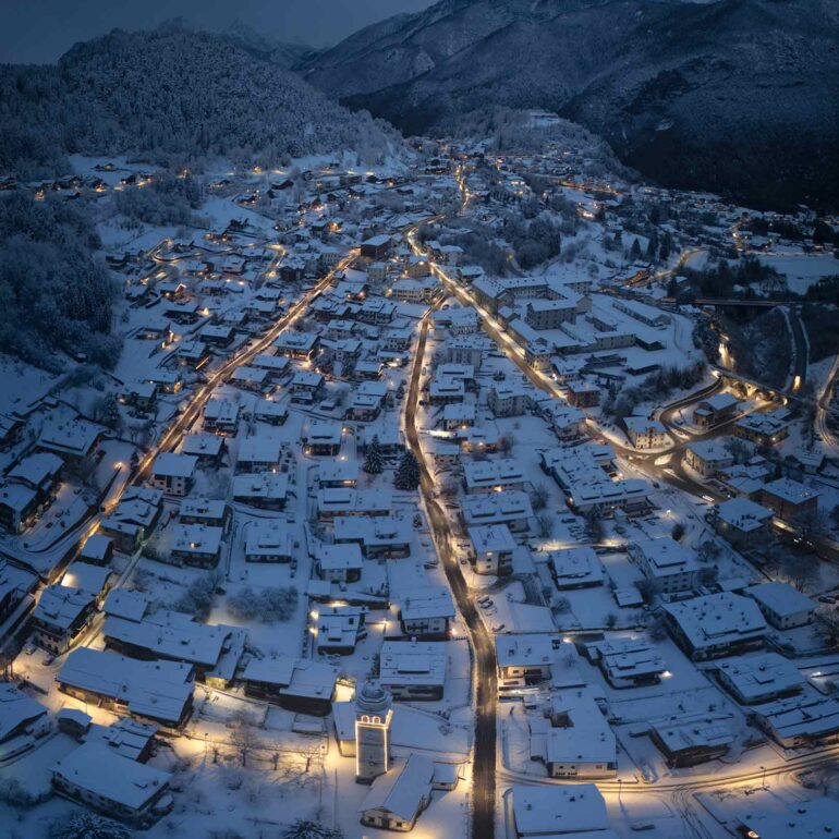Blue hour over the snow-covered village of Tai di Cadore in the Italian Dolomites, just before sunrise on a peaceful winter morning.