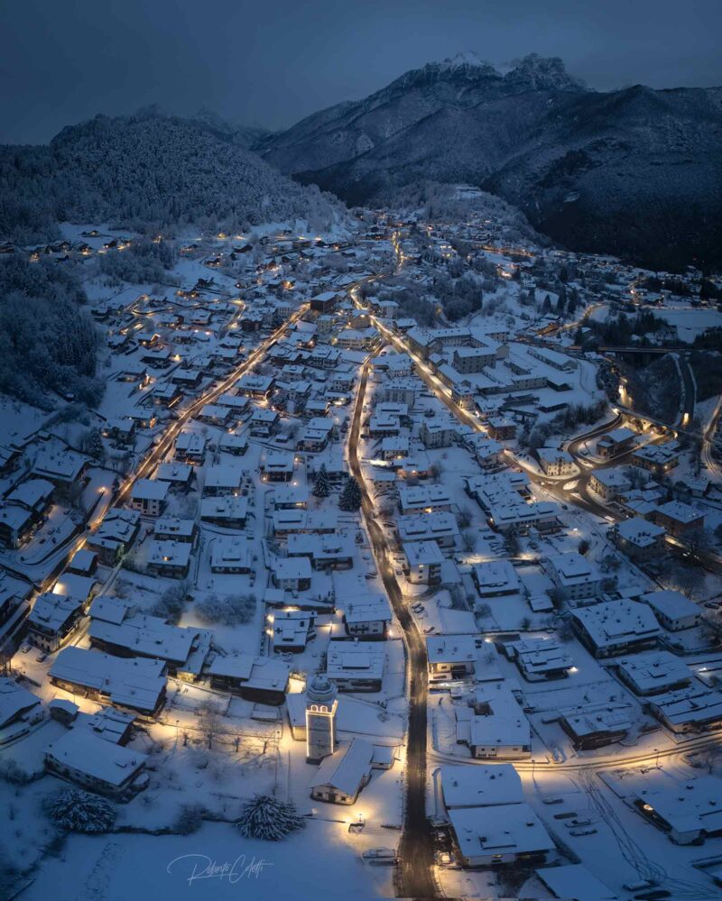 Blue hour over the snow-covered village of Tai di Cadore in the Italian Dolomites, just before sunrise on a peaceful winter morning.