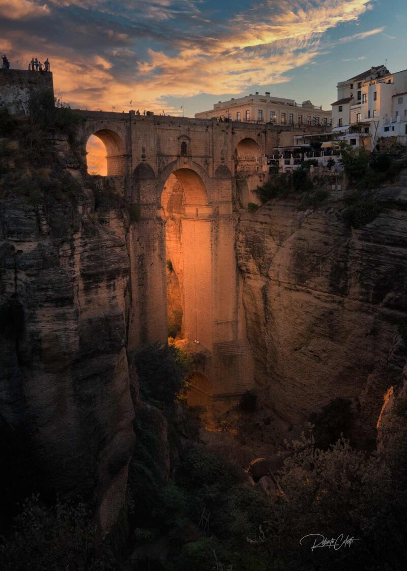 The historic Puente Nuevo illuminated by warm sunset light above El Tajo Gorge in Ronda, Andalusia, Spain.