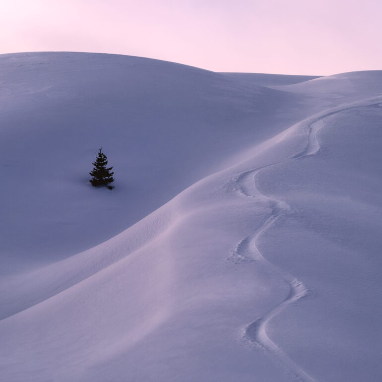 Wind-sculpted snowdrifts in the Dolomites, Italy, during a cold winter morning with soft mountain light.